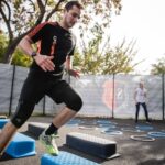 Man performing cardio exercises on outdoor agility steps during a group fitness session.