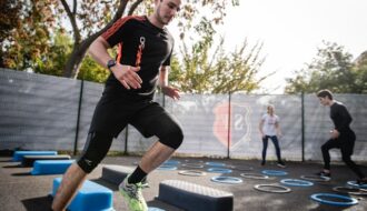 Man performing cardio exercises on outdoor agility steps during a group fitness session.