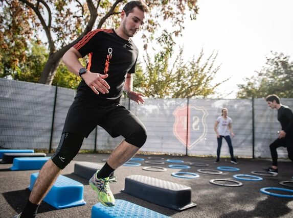 Man performing cardio exercises on outdoor agility steps during a group fitness session.
