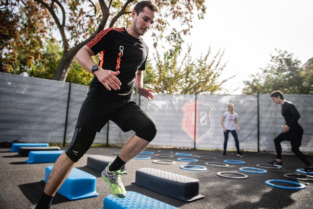 Man performing cardio exercises on outdoor agility steps during a group fitness session.