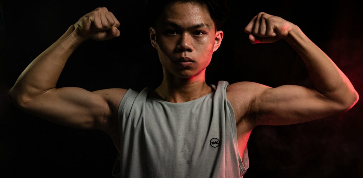 Young man flexing his muscles post-workout, highlighting strength and recovery after intense training.