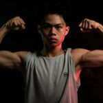 Young man flexing his muscles post-workout, highlighting strength and recovery after intense training.