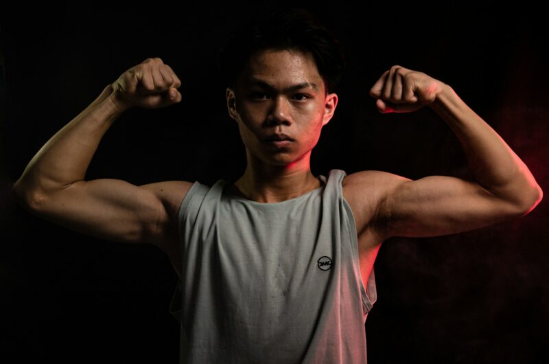 Young man flexing his muscles post-workout, highlighting strength and recovery after intense training.