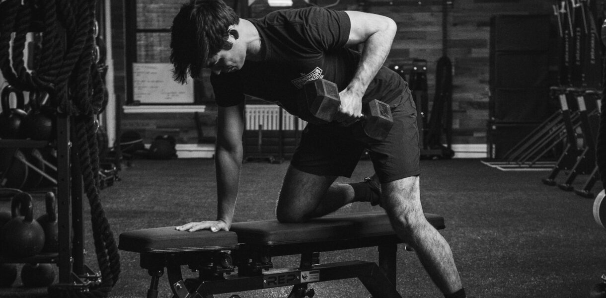 Man doing one-arm dumbbell row in gym as part of a strength training routine